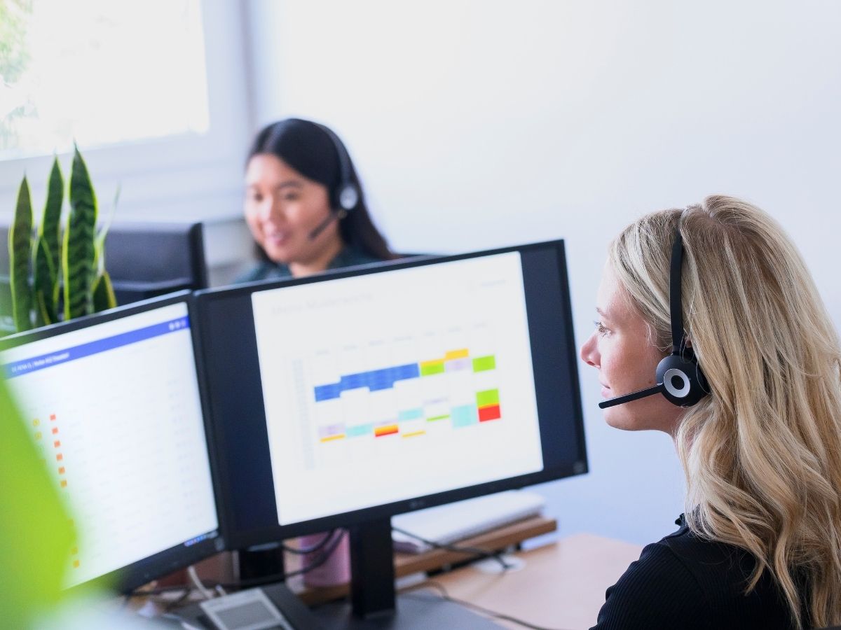 Frau mit Headset sitzt am Monitor